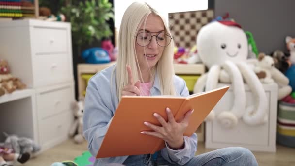 Young Blonde Woman Preschool Teacher Reading Story Book Sitting Floor — Stockvideo
