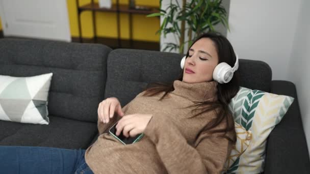 Vacker Latinamerikansk Kvinna Lyssnar Musik Med Smartphone Liggande Soffan Hemma — Stockvideo