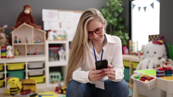 Young Blonde Woman Preschool Teacher Smiling Confident Using Smartphone Kindergarten — Stok Video