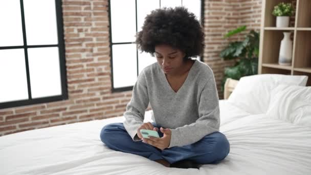 Afroamerikanerin Sitzt Mit Smartphone Schlafzimmer Auf Bett — Stockvideo