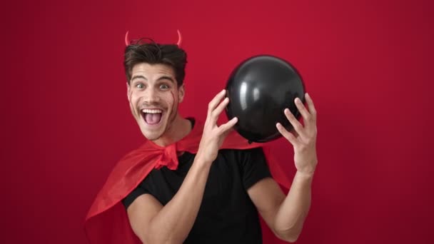 Young Hispanic Man Wearing Devil Costume Holding Balloon Isolated Red — Stock Video