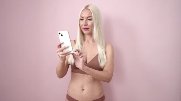 Młoda Blondynka Bieliźnie Zrobić Selfie Przez Smartfona Odizolowanym Różowym Tle — Wideo stockowe