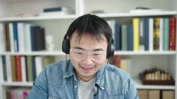 Fiatal Kínai Diák Számítógéppel Fejhallgatóval Könyvtár Egyetemen — Stock videók