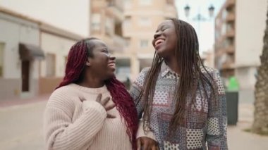 Two african american women smiling confident speaking at street