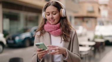 Young woman smiling confident listening to music at street