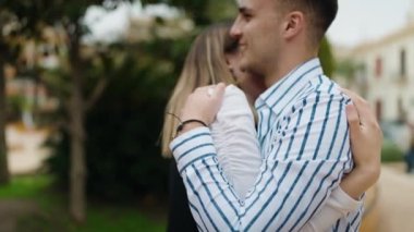 Man and woman couple smiling confident hugging each other at park