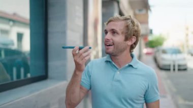 Genç adam gülümsüyor. Kendine güveniyor. Sokakta akıllı telefondan konuşuyor.