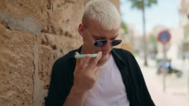 Genç beyaz adam gülümsüyor. Kendine güveniyor. Akıllı telefondan konuşuyor.