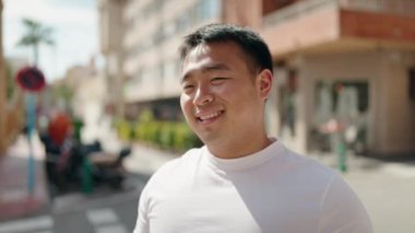 Young chinese man smiling confident standing at street
