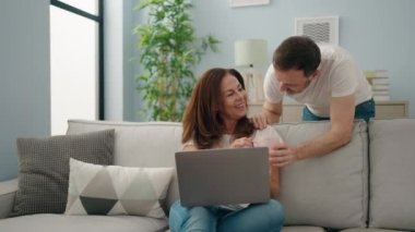 Kadın ve erkek evde kahve içerken dizüstü bilgisayar kullanıyorlar.
