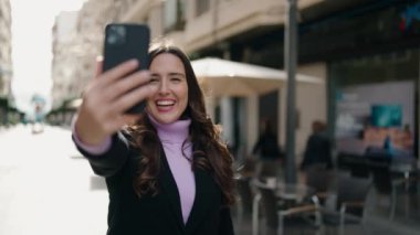 Young hispanic woman smiling confident having video call at street
