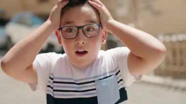 Sevimli İspanyol çocuk, şaşırmış bir ifadeyle caddede duruyor.