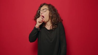 Kırmızı arka planda öksüren orta yaşlı bir kadın.