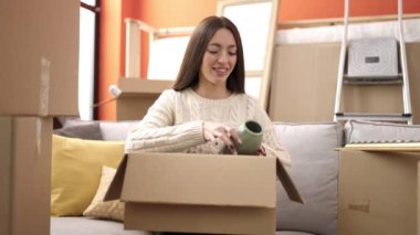 Genç, güzel, İspanyol bir kadın gülerek yeni evindeki karton kutuları açıyor.