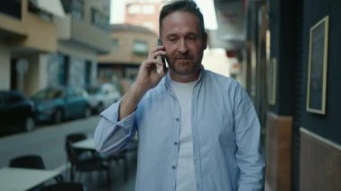 Kafkasyalı genç adam akıllı telefondan konuşuyor. Sokakta nöbet tutuyor.