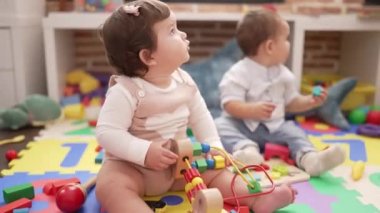 Anaokulunda yerde oturmuş oyuncaklarla oynayan iki çocuk.