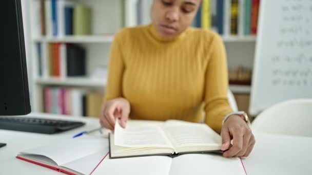 若いアフリカ系アメリカ人の女性が図書館で本を読んでいる — ストック動画