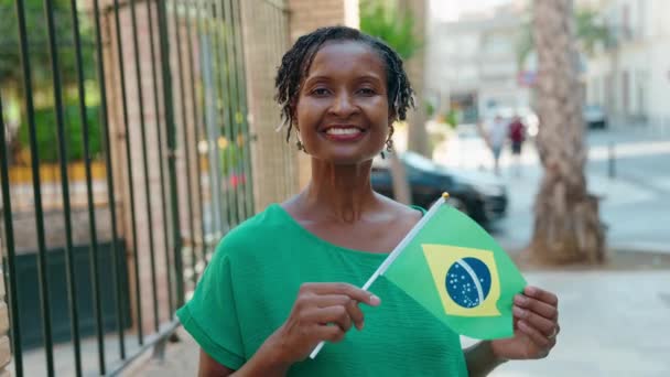 中年非洲妇女微笑着 自信地在街上高举着厚脸皮的国旗 — 图库视频影像