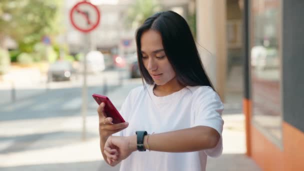 Młoda Piękna Latynoska Kobieta Pomocą Smartfona Patrząc Zegarek Ulicy — Wideo stockowe