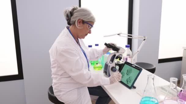 Middle Age Grey Haired Woman Wearing Scientist Uniform Using Microscope — Stock video
