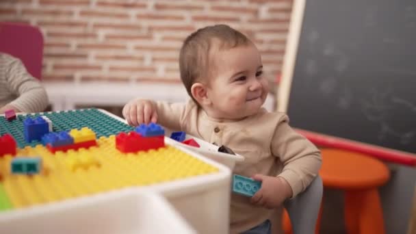 Adorable Toddler Holding Plastic Construction Blocks Sitting Table Kindergarten — ストック動画