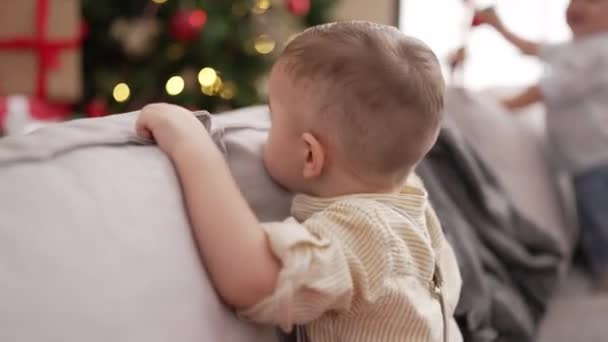 Två Bedårande Småbarn Ler Tryggt Stående Soffan Vid Julgranen Hemma — Stockvideo