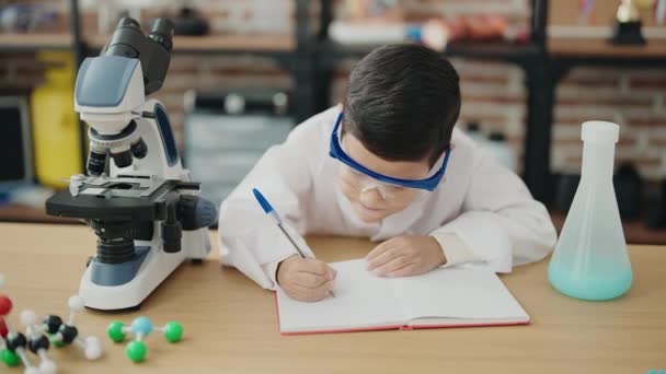 Αξιολάτρευτο Ισπανόφωνο Αγόρι Φοιτητής Χρησιμοποιώντας Μικροσκόπιο Γραφής Στο Σημειωματάριο Στην — Αρχείο Βίντεο