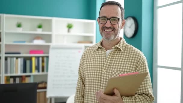 Middle Age Man Teacher Smiling Confident Holding Clipboard Classroom — Stockvideo