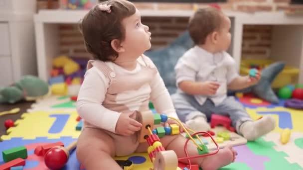 幼稚園の床に座っておもちゃで遊んでいる2人の幼児 — ストック動画