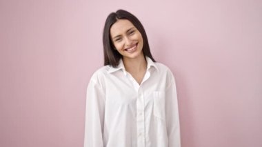 Genç, güzel İspanyol kadın kendine güvenen, pembe arka planda öpüşen.