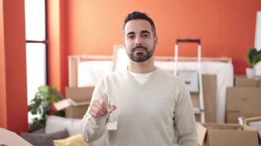 Young hispanic man smiling confident holding key at new home