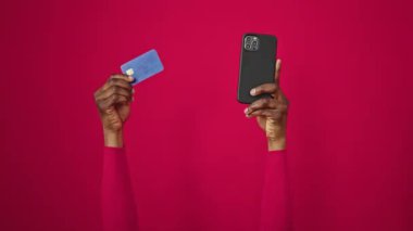 Afrika kökenli Amerikalı bir kadının elinde akıllı telefon ve kredi kartı var.