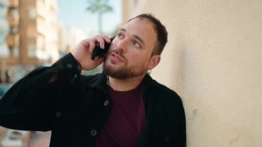 Sokakta akıllı telefondan konuşan genç ve cüsseli adam.