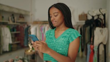 Giyim mağazasında akıllı telefon kullanan Afrikalı Amerikalı kadın müşteri
