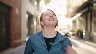 Genç kızıl saçlı kadın spor giyer koşar ve caddede kronometre arar.