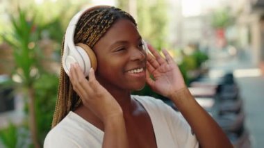 Afro-Amerikalı kadın kahve dükkanının terasında müzik dinliyor ve dans ediyor.