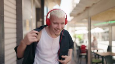 Sokak ortasında müzik dinleyen ve dans eden beyaz bir genç.