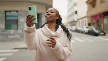 Afro-Amerikalı kadın sokakta akıllı telefon kullanarak kendine güveniyor.