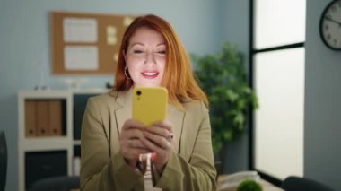 Young redhead woman business worker using smartphone at office