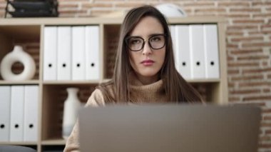 Güzel İspanyol iş kadını ofiste şüphe dolu bir dizüstü bilgisayar kullanıyor.