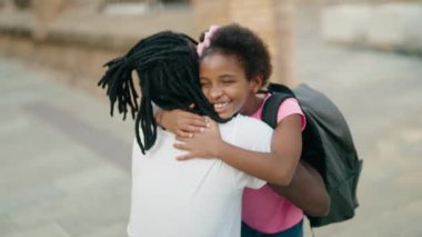 Baba ve kızı gülümsüyor okulda birbirlerine sarılıyorlar.