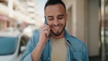 Genç İspanyol adam akıllı telefondan konuşuyor. Sokakta kazanan yüz ifadesiyle.
