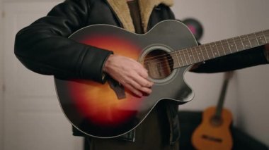Müzisyen adam müzik stüdyosunda klasik gitar çalıyor.