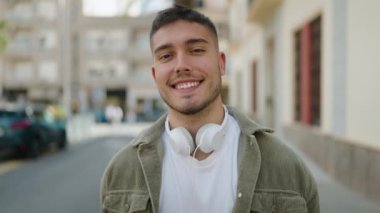 Sokakta kulaklık takarak gülümseyen İspanyol genç adam.