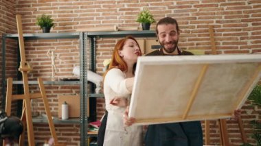 Man and woman artist couple looking canvas draw at art studio