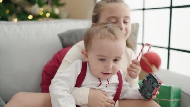 Broer Zus Knuffelen Elkaar Zittend Bank Door Kerstboom Thuis — Stockvideo