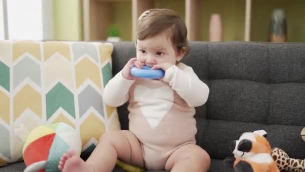 Bedårande Småbarn Bita Plast Båge Sitter Soffan Hemma — Stockvideo