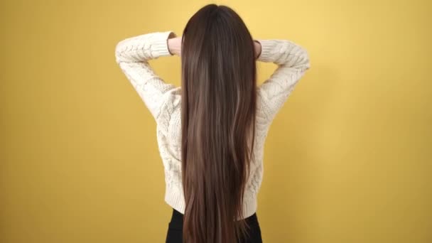 Молодая Красивая Латиноамериканка Расчесывает Волосы Назад Изолированном Желтом Фоне — стоковое видео