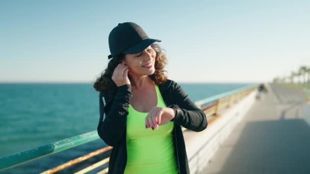 Middle Age Woman Wearing Sportswear Running Looking Stopwatch Seaside — Αρχείο Βίντεο