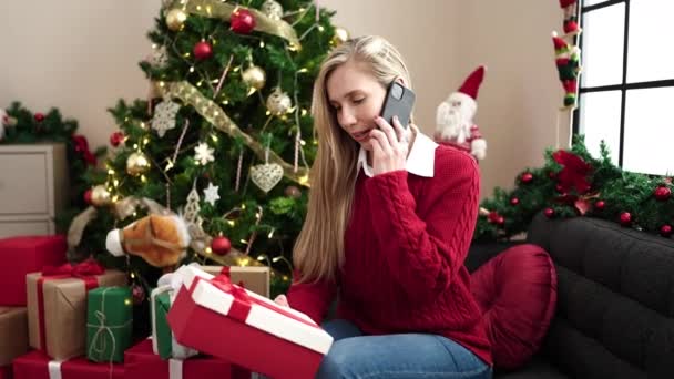 若いですブロンド女性話して上のスマートフォン保持クリスマスギフトに家 — ストック動画
